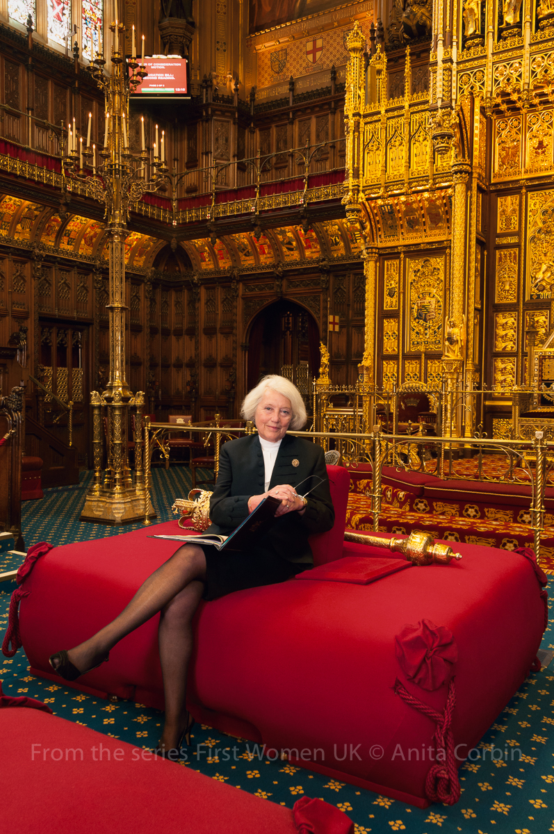 A woman sitting on a large red cushioned seat in the House of Lords.