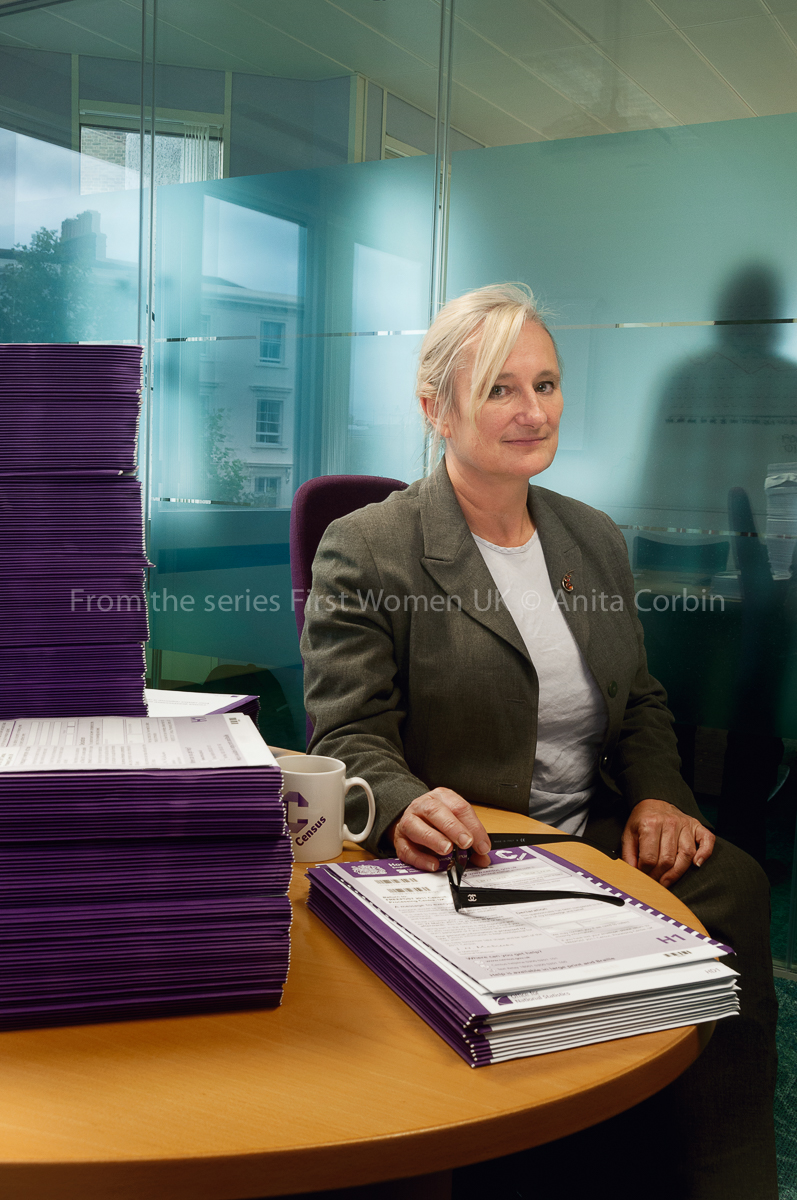 A woman sitting at a round table with stacks of purple files in front of her.